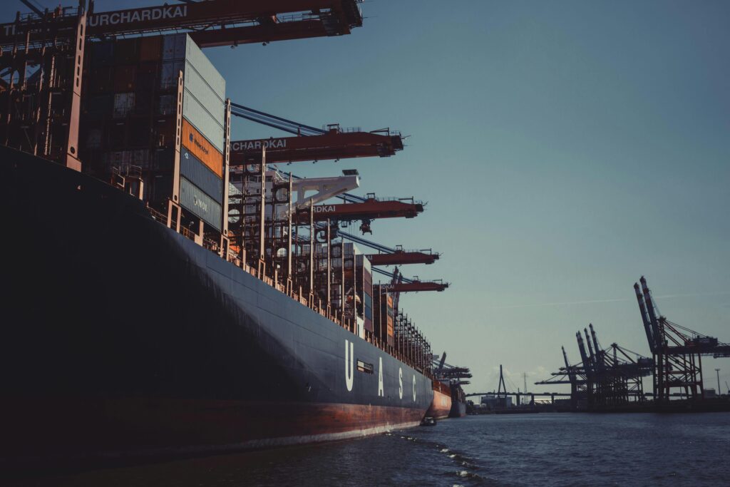 Cargo ship at berth with container cranes loading, representing commercial imports cleared under CARM