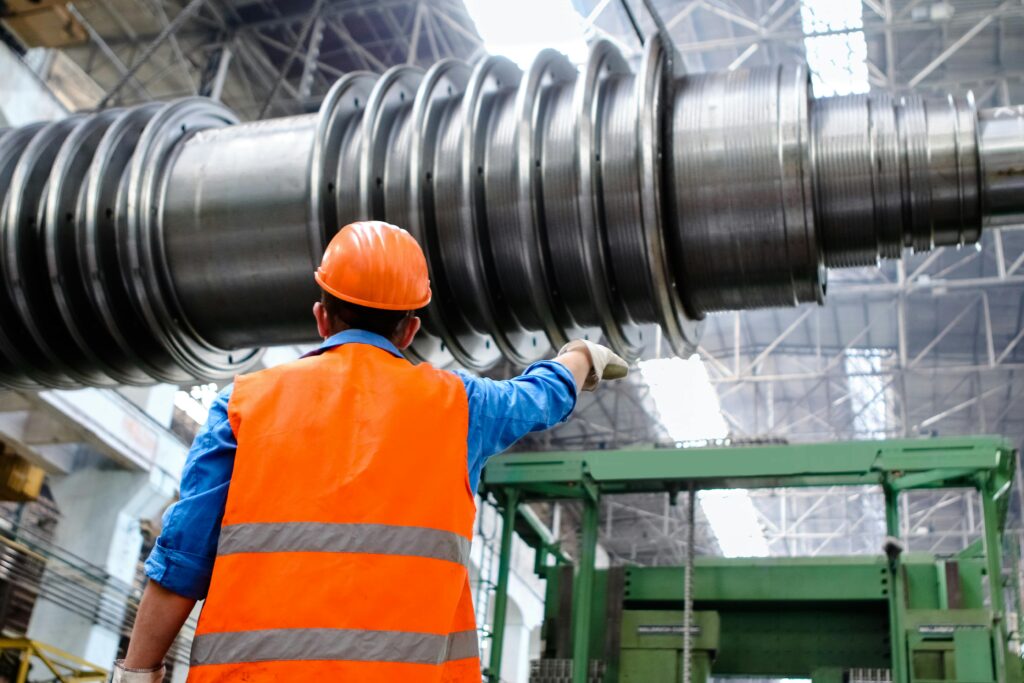 Industrial worker handling large ducting on a plant floor — manufacturing insurance for Canadian plants