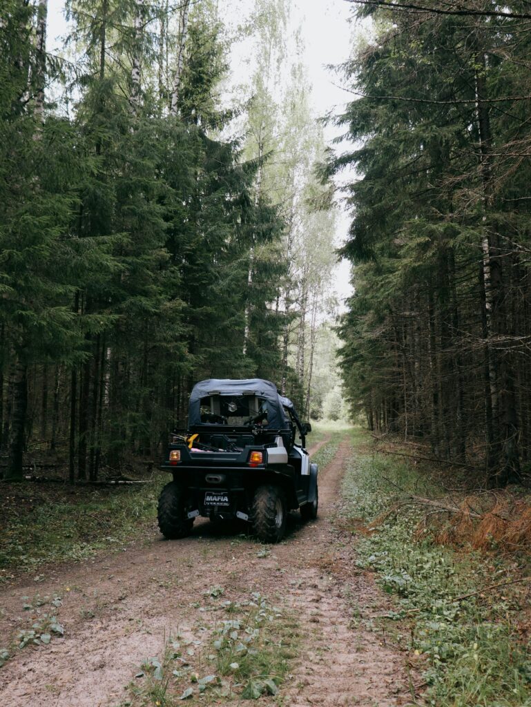 An ATV navigating a scenic dirt path through a dense forest setting.