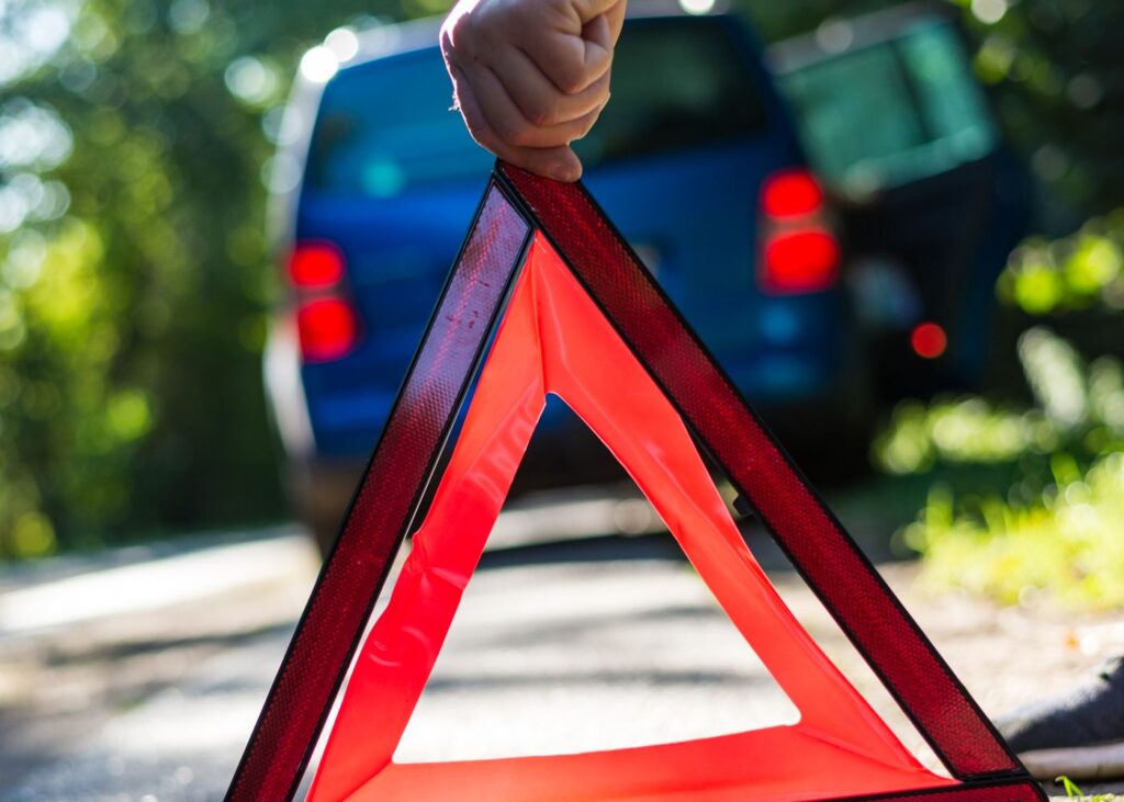 Driver placing an emergency warning triangle on the road behind a damaged vehicle