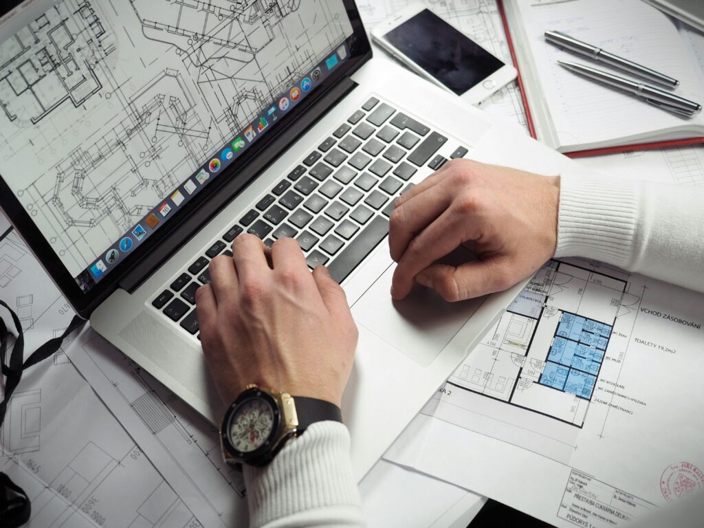 Contractor estimating a United States tender with drawings and a laptop before posting a US bid bond