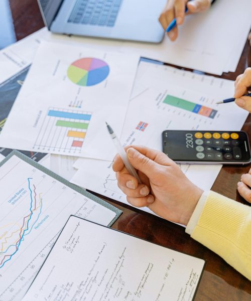 A close-up of businesspeople analyzing financial data and charts during a meeting.