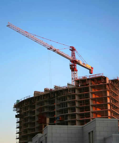Tower crane on a high-rise building under construction at sunset, showcasing modern urban development.